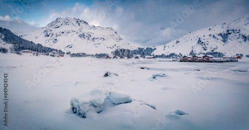 Panoramic winter view of Justad fishing village on Vestvagoy island with snowy peaks on background. Gloomy morning scene of Lofoten Islands after huge snowfall. Traveling concept background. photo