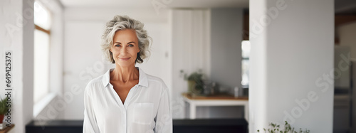 Portrait stylish elegant mature middle aged woman posing indoors, cute smiling scary lady with gray hair looking at camera. Copy space