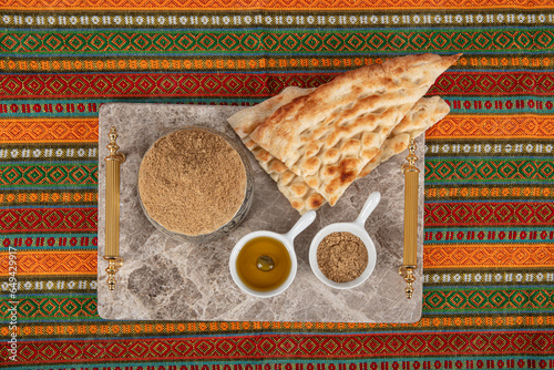 Za'atar is a culinary herb or family of herbs. It is also the name of a spice mixture typically used as a condiment, which contains the herb along with toasted sesame seeds, dried sumac, and often sal photo