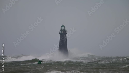 Hurricane high winds causing waves to crash against a lighthouse slow motion