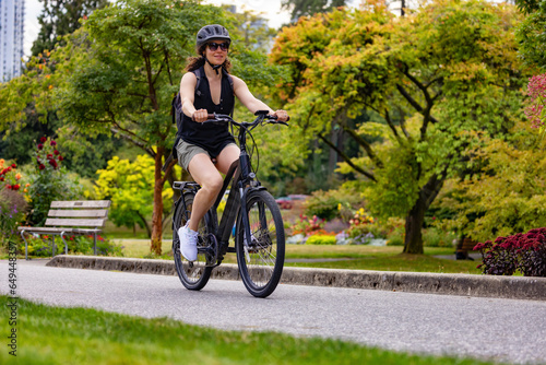 Photos Fit Caucasian Woman riding an Electric Bicycle on a trail in Stanley Park, Downtown Vancouver, British Columbia, Canada