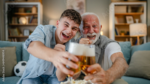 teenager and his grandfather senior man watch football game at home