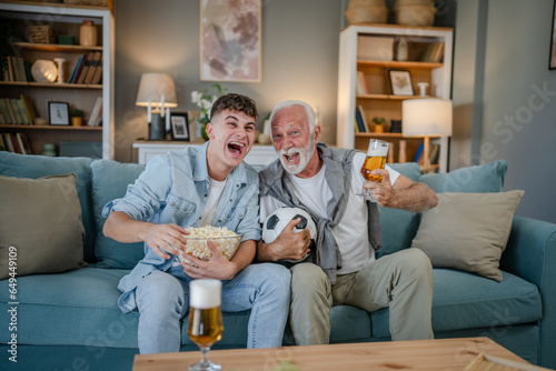 teenager and his grandfather senior man watch football game at home