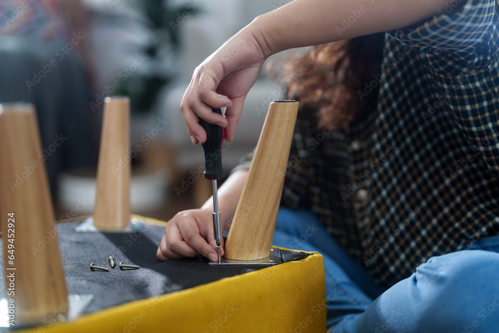 Asian woman assembles furniture by herself at home Asian woman assembles furniture by herself at home