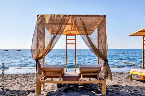 Fira, Greece - July 20, 2023: Palapas and beach chairs on the island of Santorini in Greece 