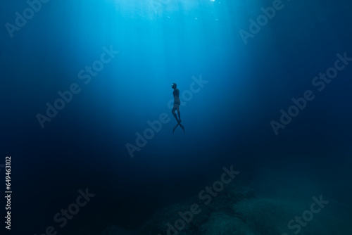 Freediver Swimming in Deep Sea With Sunrays. Young Man DIver Eploring Sea Life. © Lukas Gojda