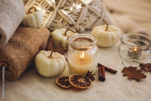 Autumn composition with aromatic candle, dry citrus, cinnamon, anise. Aromatherapy on a grey fall morning, atmosphere of cosiness and relax. Wooden background, pumpkin as decor