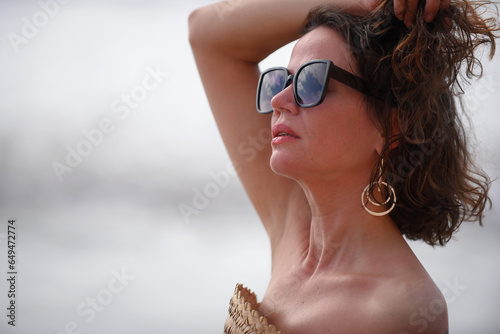 young relaxed woman on the beach model summer coastline light clothing lipstick sunglasses hair and nature