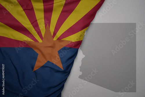 big waving national colorful flag and map of arizona state on the gray background. photo