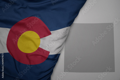 big waving national colorful flag and map of colorado state on the gray background. photo