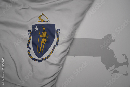 big waving national colorful flag and map of massachusetts state on the gray background. photo