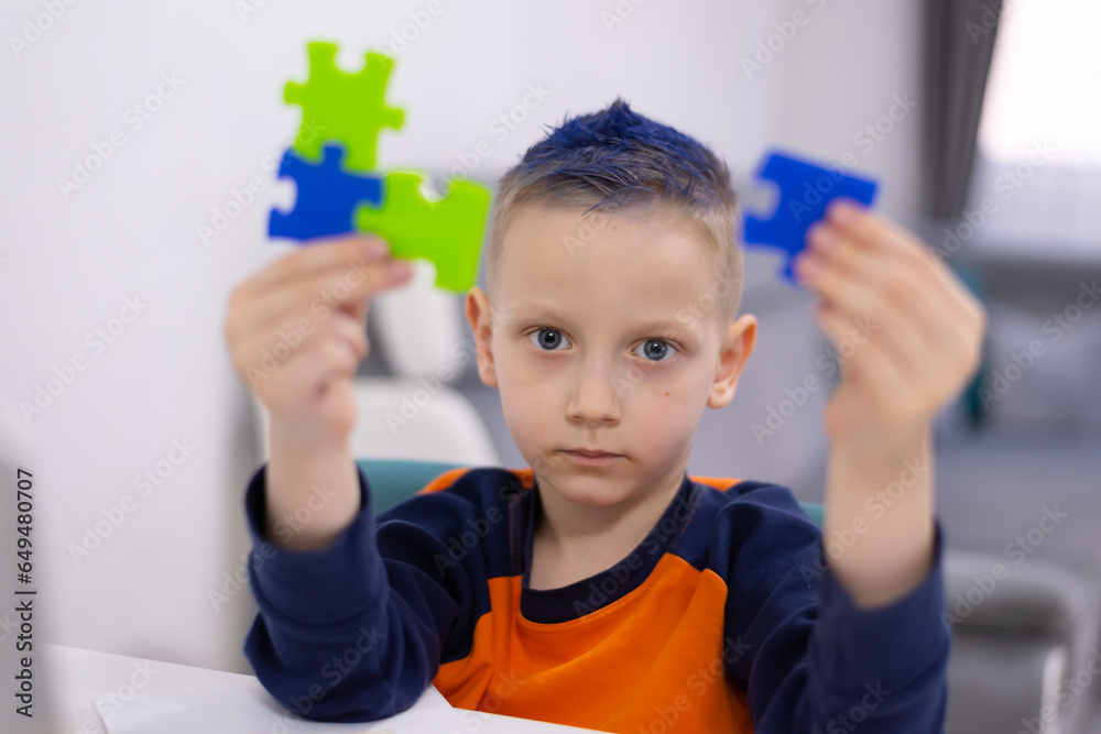 Kid boy is putting together a big colored puzzle Kid boy is putting together a big colored puzzle