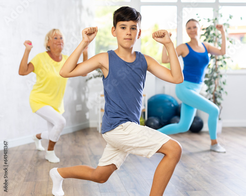 Active family three generations of mother, grandmother and teen son are learning sports Latin American dances in studio class. Joint pastime, active hobby