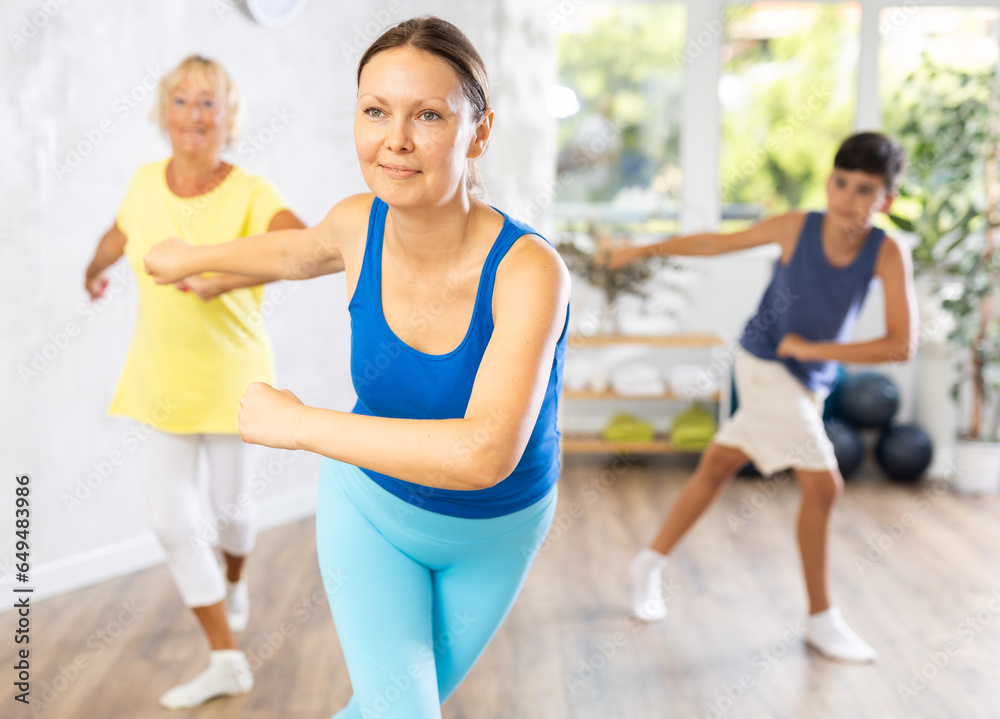 Dynamic middle-aged woman practicing dance movements in group during training session
