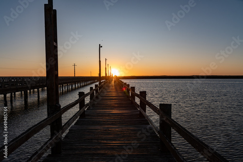 Atardecer en un muelle de madera donde se puede pescar, mar calmo photo