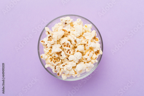 Tasty popcorn in bowl on color background, top view