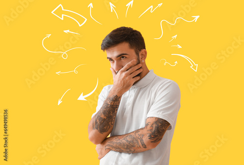 Portrait of tattooed man on yellow background. Concept of choice