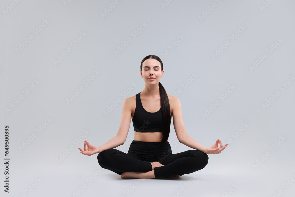 Beautiful young woman practicing yoga on grey background. Lotus pose Beautiful young woman practicing yoga on grey background. Lotus pose
