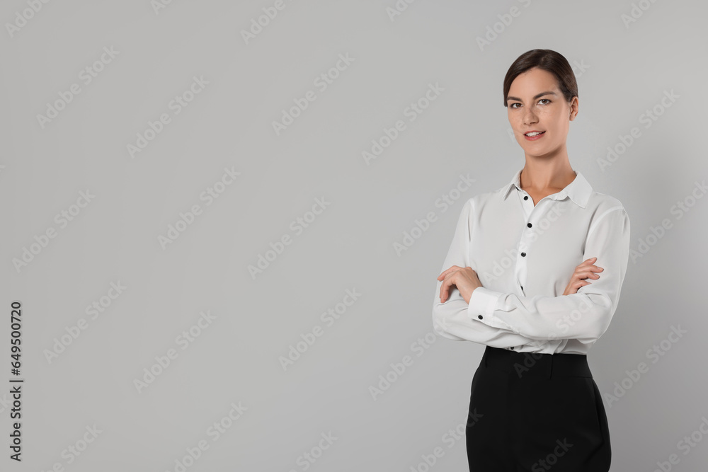 Young secretary with crossed arms on light grey background, space for text Young secretary with crossed arms on light grey background, space for text