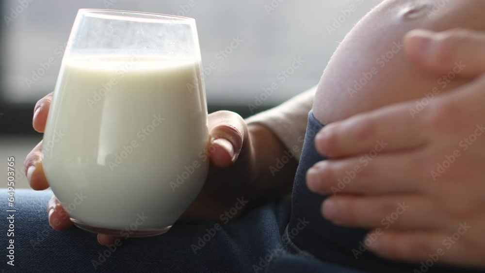 Pregnant woman drinking milk at home. Staying hydrated and consuming