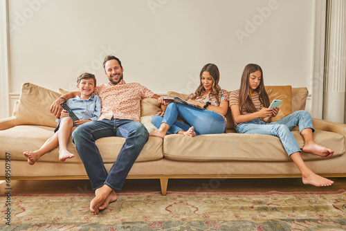 Smiling family with two children (8-9, 12-13) relaxing on sofa photo