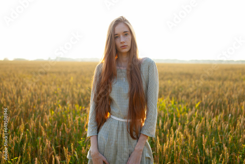 Portrait of young woman looking at camera while standing in field photo