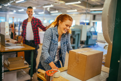 Young Caucasian woman sealing a box while working in warehouse