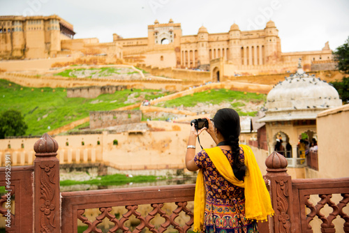 Photography Woman tourist taking a photo of the Amer fort, located in Jaipur, India