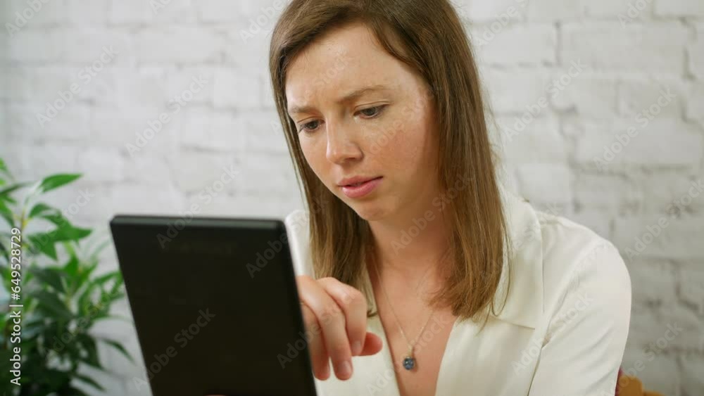 A happy young woman using a tablet sitting at a desk A happy young woman using a tablet sitting at a desk