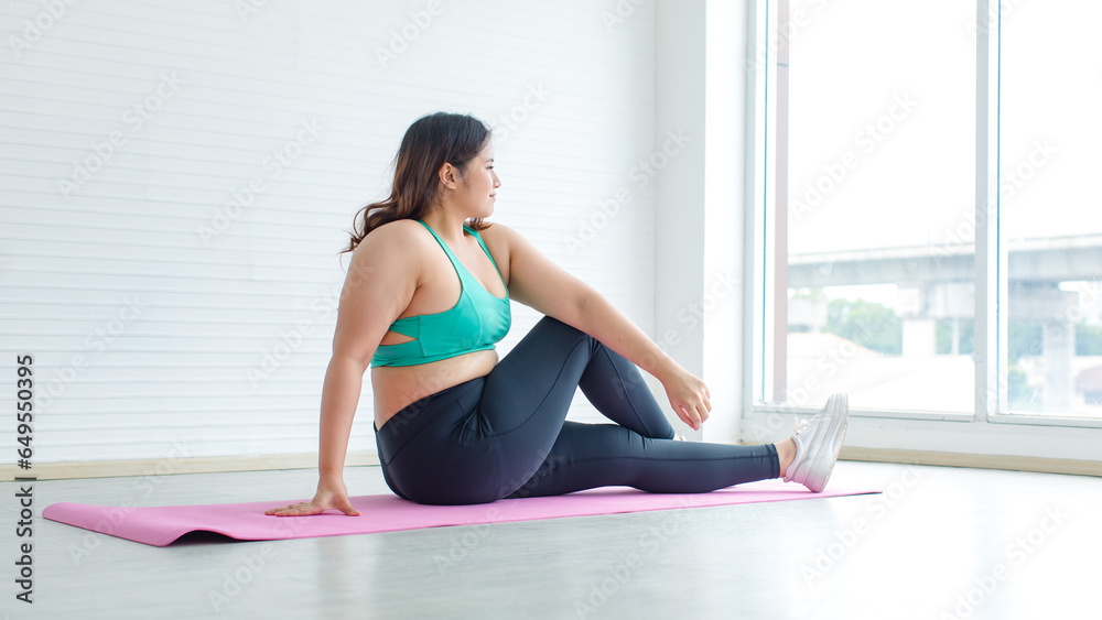 Asian young sexy chubby fat unhealthy oversized female model in sports bra legging sneakers sitting stretching arms legs on yoga pilates mat ready for training exercise practicing in home fitness gym Asian young sexy chubby fat unhealthy oversized female model in sports bra legging sneakers sitting stretching arms legs on yoga pilates mat ready for training exercise practicing in home fitness gym
