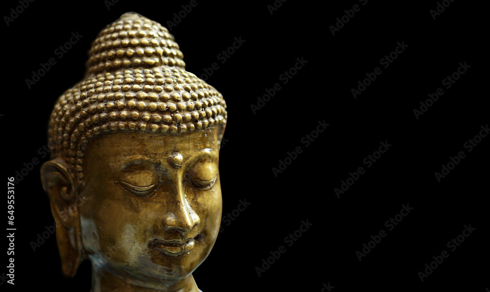 golden statue of a smiling buddha head on a black background