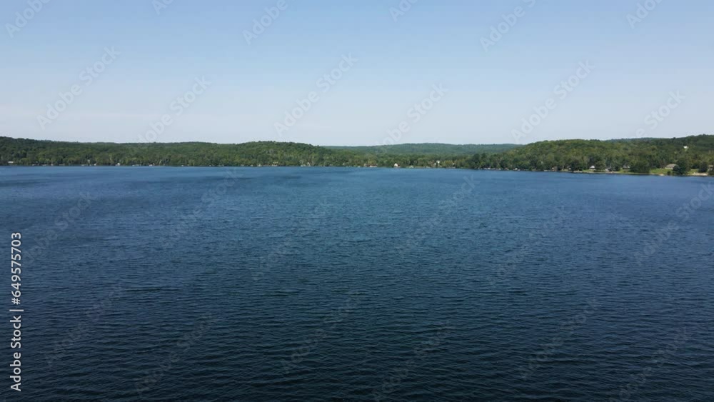Stunning blue sky reflects on ripple windy lake surrounded by thin green band of rolling hills Stunning blue sky reflects on ripple windy lake surrounded by thin green band of rolling hills