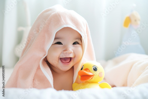 Happy Asian little baby wearing hooded towel sitting on the bed after bath
