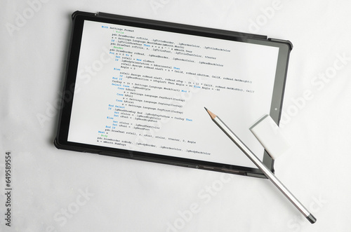 Programming and coding concept. Writing utensils - a pencil and an eraser lie on top of the screen with a program listing