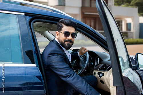 Foto Handsome successful rich wealthy indian businessman in formal wear and sunglasses getting out of luxury car