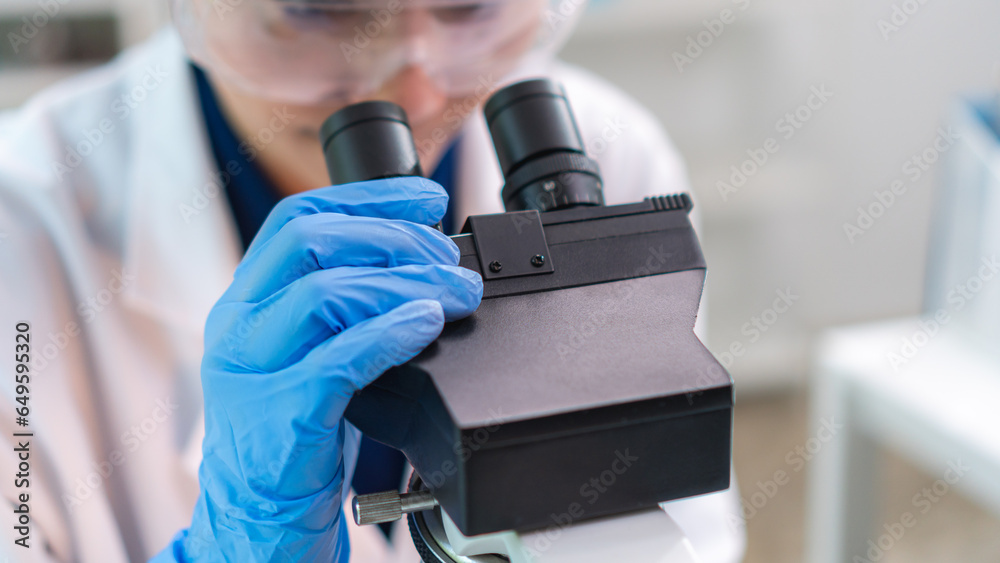 Close up scientist wearing glassware working with microscope for research and analysis experiment medical biotechnology medicine pharmaceutical healthcare
