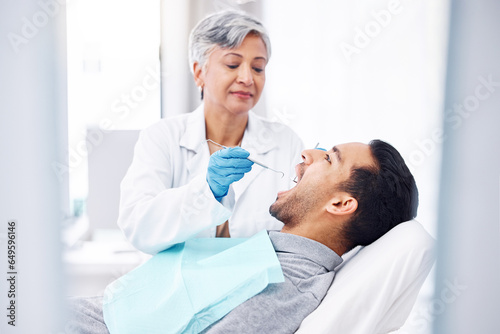 Woman, dentist and check teeth of man with tools for dental cosmetics, healthcare assessment and medical consulting. Patient, tooth and oral cleaning with mirror, excavator and orthodontic surgery photo
