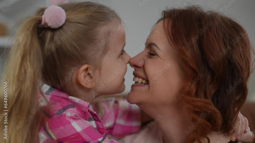 Closeup side view faces of smiling woman and girl rubbing noses indoors. Carefree happy loving Caucasian mother and daughter enjoying leisure on weekend at home Closeup side view faces of smiling woman and girl rubbing noses indoors. Carefree happy loving Caucasian mother and daughter enjoying leisure on weekend at home