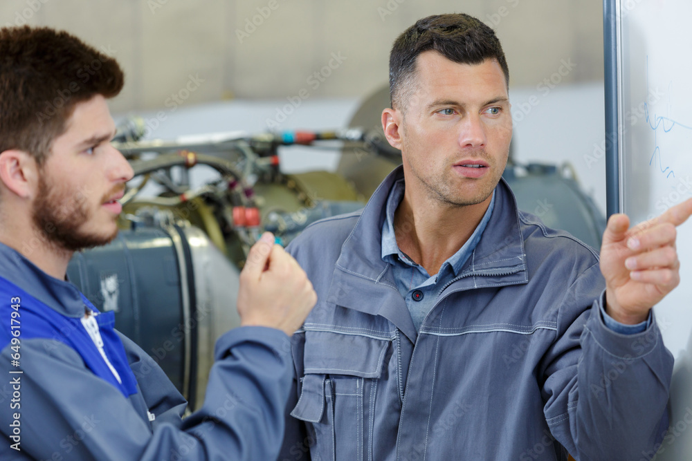 two mechanics working on a small aircraft in a hangar two mechanics working on a small aircraft in a hangar