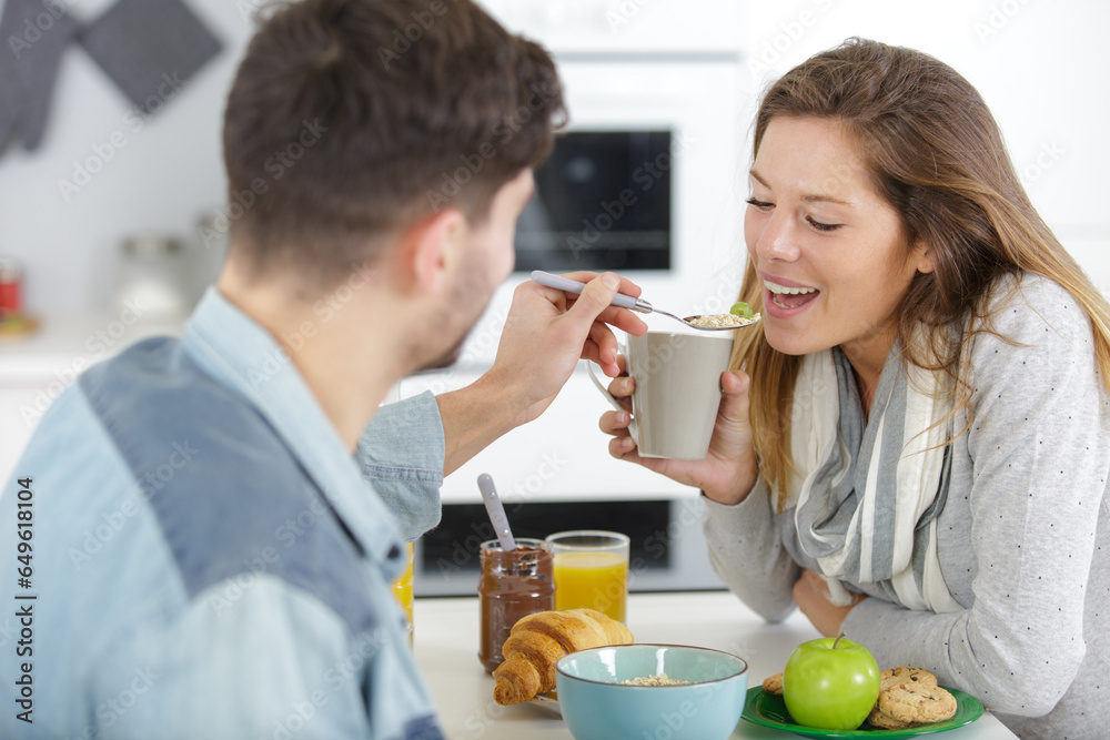 young man is feeding breakfast to his girlfriend young man is feeding breakfast to his girlfriend