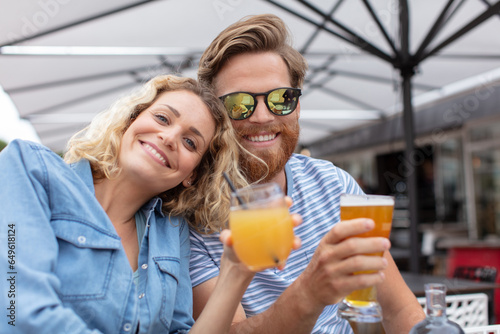 smiling couple on a terrace holding drinks