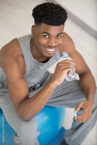 muscular sportsman resting and drinking wtaer photo