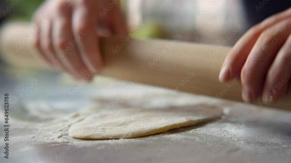 A person flattens dough on a table top A person flattens dough on a table top