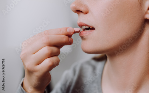 Dietary supplement concept. Close up of young caucasian woman holding little medical pill  take or eat vitamin C  D for treatment for skin  hair and nail strengthen  healthcare