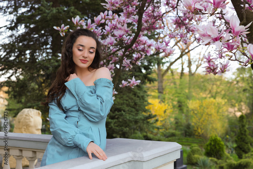 Beautiful woman near blossoming magnolia tree on spring day