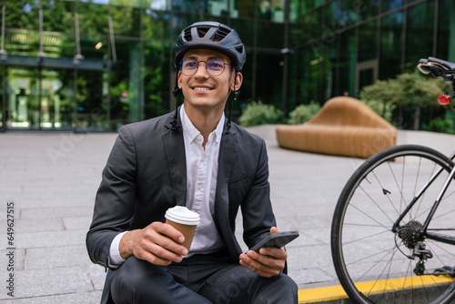 Young man in a suit and protective hempet with a coffee cup in hand photo