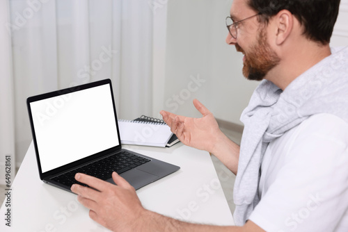 Man having video chat via laptop at white table indoors, selective focus