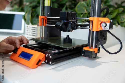 Man checking 3d printer, process of making things on 3d printer in laboratory.