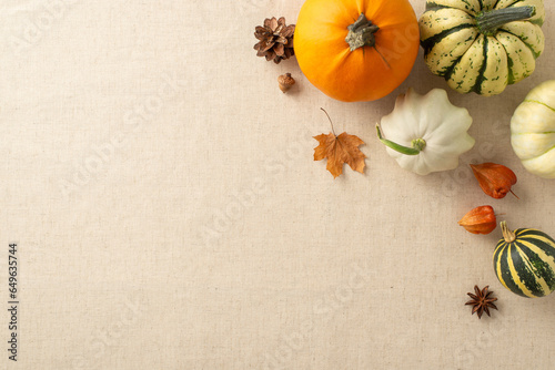 Warm and inviting Thanksgiving display: Top view of beige tablecloth arrangement, accompanied by pumpkins, pattypans, physalis, acorn and anise. Your text or message can grace this space