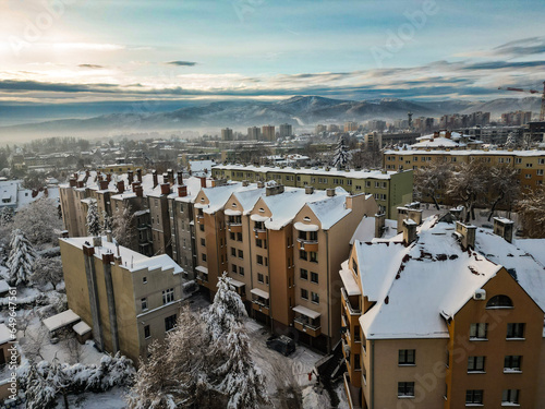 Budynki i bloki mieszkalne miasta Bielsko-Biała w zimie widoczne z lotu ptaka, w tle góry Beskidu i lekko zachmurzone niebo  © Andrzej